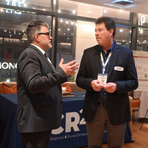 dr jerry everett speaking to a conference attendee in front of the cr2c2 booth